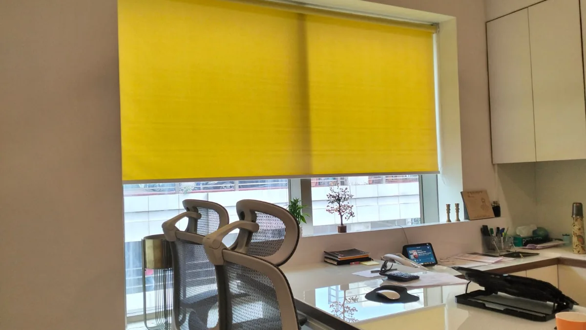 Roller blind lowered over an office workstation window