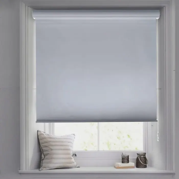 White roller blind half lowered above a window seat