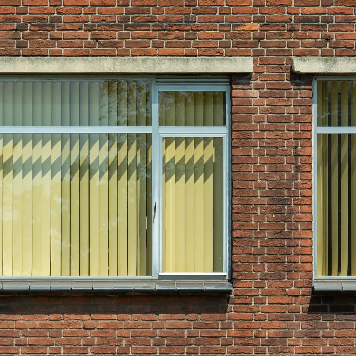 Vertical blinds hanging in a row of office windows