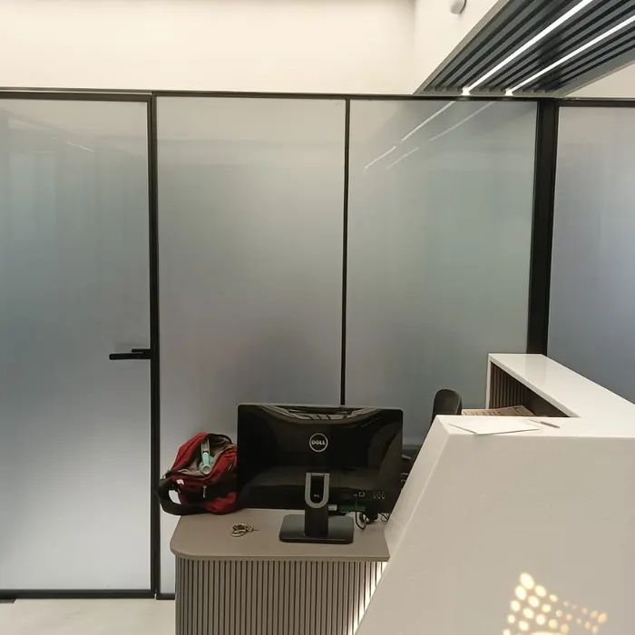Reception desk behind black-framed frosted glass partitions