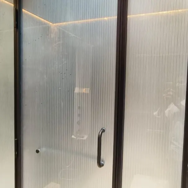 Reeded glass shower enclosure with a steel handle