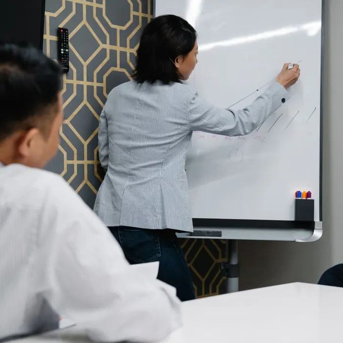 Presenter writing across a wall-wide dry-erase surface